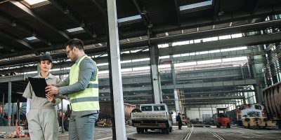 Manager and female worker at depot with workshops for the repair of train wagons.